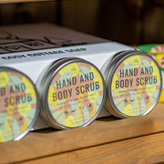 Three tins of Cosy Cottaage hand and body scrub standing upright on a wooden shelf