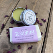uplifting geranium travel soap bar and natural lip balm on a bed of purple petals