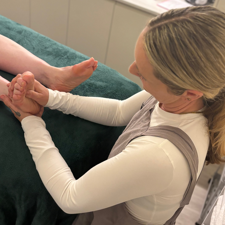 Woman receiving a reflexology treatment foot massage in a clinical setting.