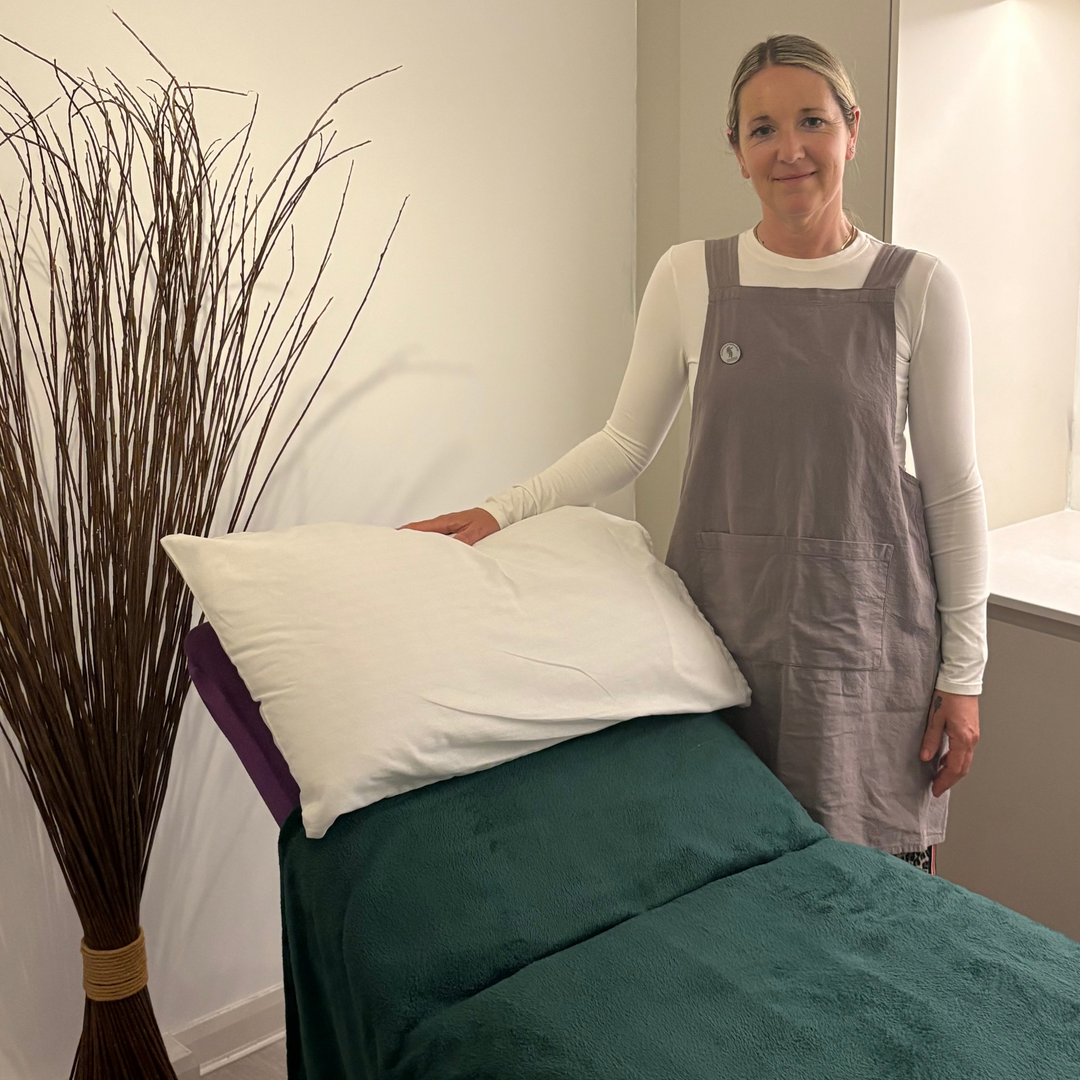 Reflexologist in a spa setting arranging pillows on a massage table