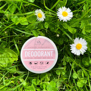 tin of Cosy Cottage Soap Natural Deodorant on grass and clover leaves with three daisy flowers
