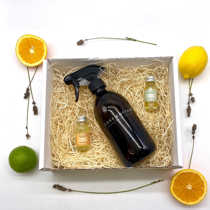 Set of cleaning spray concentrates and a spray bottle in a box with fruit on a white background