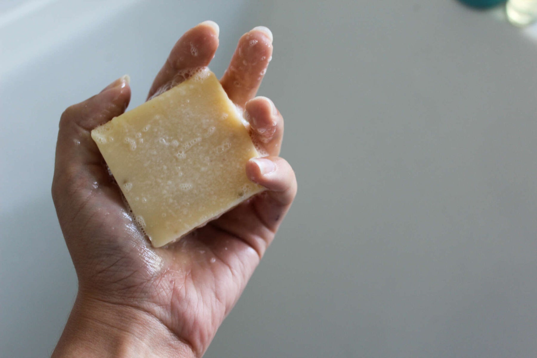natural soap bar with suds being held in hand hand