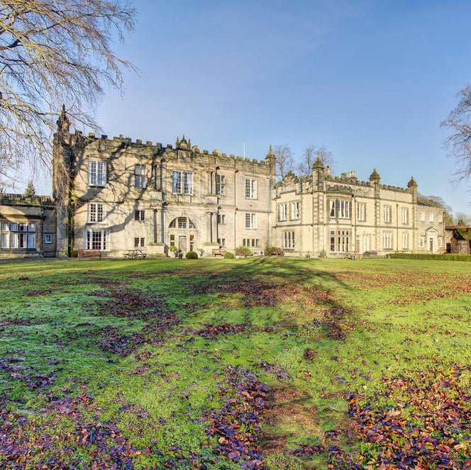 Large stone mansion with a well-maintained garden in the foreground