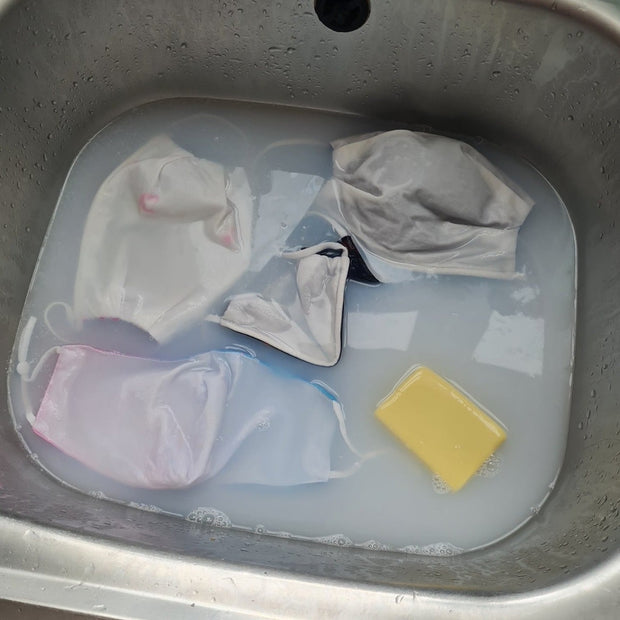sink of clothes soaking in soapy water