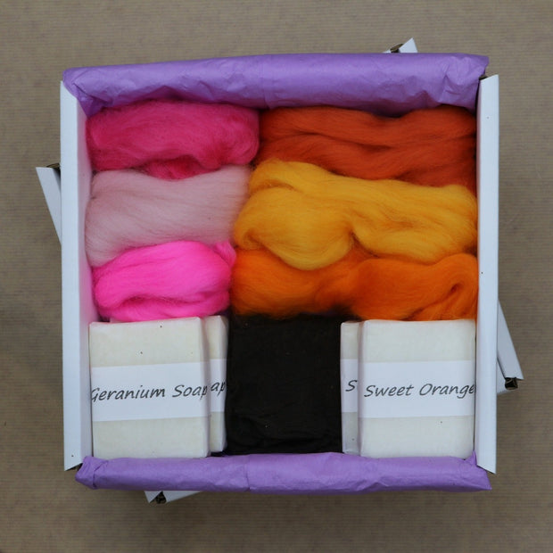 Gift box containing roving wool in pinks and oranges, four soap bars, pair of tights
