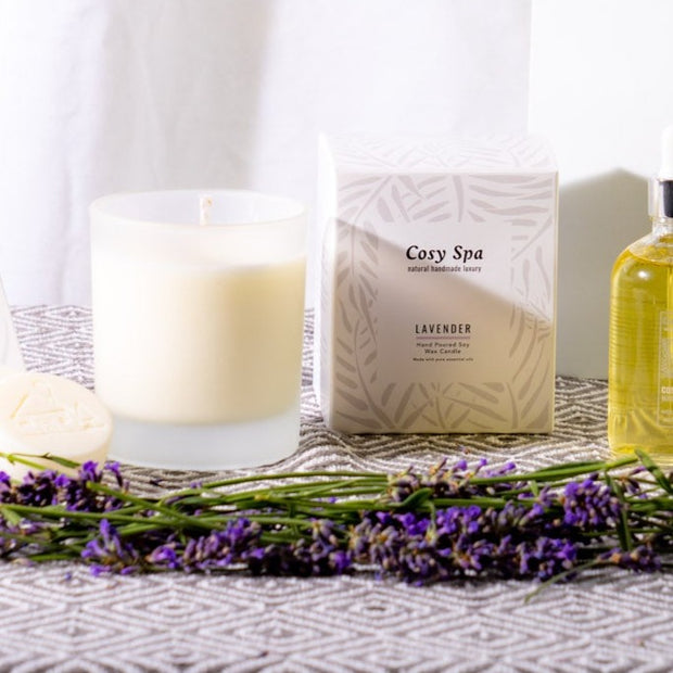 lavender candle in frosted glass jar with Cosy Spa branded candle box and lavender flowers on geometric table cloth