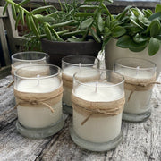 Five Cosy Cottage lemongrass soy wax candles in glass jars on an outdoor table with plants