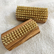 Two olive wood nail brushes on a towel