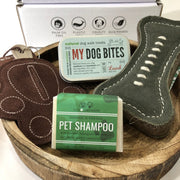 bar of pet shampoo, tin of dog treats, bone-shaped dog toy and paw shaped poop bag holder