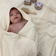 baby wearing Cosy Cuddles hooded towel, with Cosy Cuddles baby balm, soap and barrier cream 