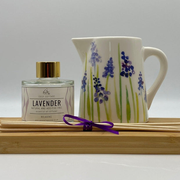 Cosy Cottage Lavender diffuser with wooden reeds and flowery jug on a wooden board