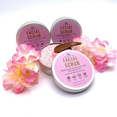 facial scrub with pink jojoba seeds, geranium and patchouli essential oils, tin open showing product with wooden spatula