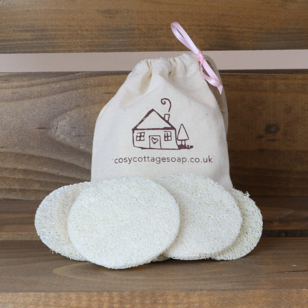 four natural loofah discs with cotton drawstring bag displayed in a wooden crate