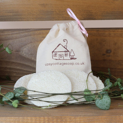 four natural loofah discs with cotton drawstring bag displayed in a wooden crate