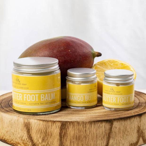 mango butter and lemon foot balm in 30ml and 120ml glass jars with fresh lemon and mango