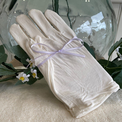 pair of unbleached cotton gloves tied with a ribbon
