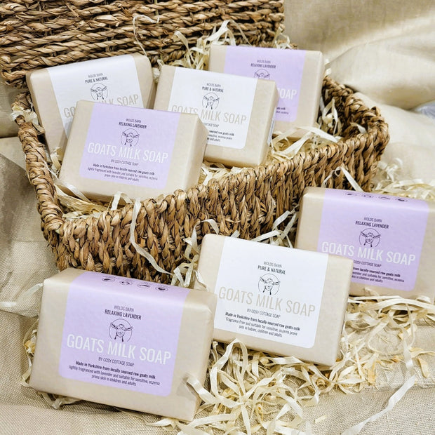Seven goats milk soap bars, some unfragranced, some gently fragranced with lavender essential oil. Displayed in a rustic basket.