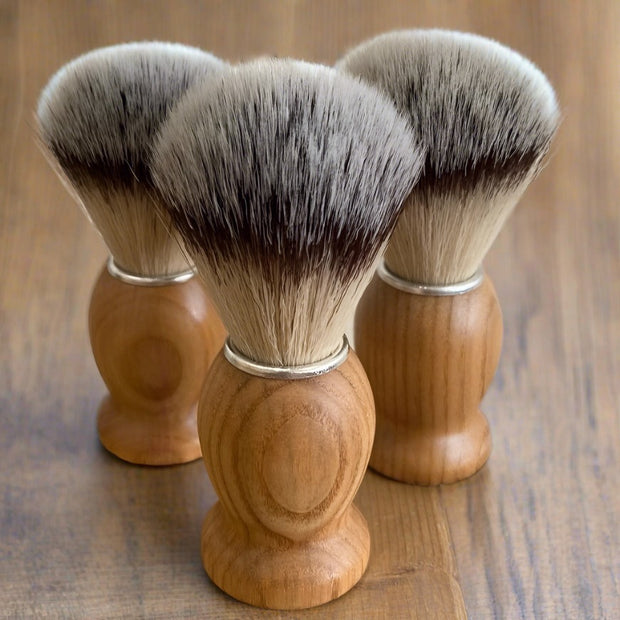 natural shaving brushes with synthetic bristles and beech handle on a wooden shelf