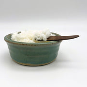 Ceramic dish containing Whitby sea salt scrub and wooden spatula