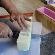 natural soap bar being cut by hand with a knife