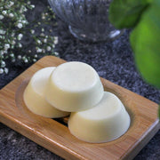 three solid conditioner roundels stacked on a wooden soap dish