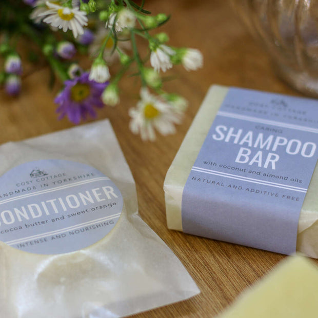 solid conditioner bar and natural shampoo bar in plastic free wrapping on a wooden table