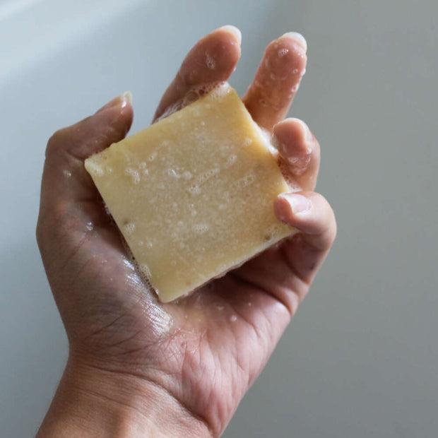 natural soap bar with suds held in a hand