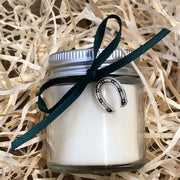 handmade soy wax candle with green ribbon on a bed of straw