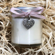 handmade soy wax candle with pink ribbon on a bed of straw