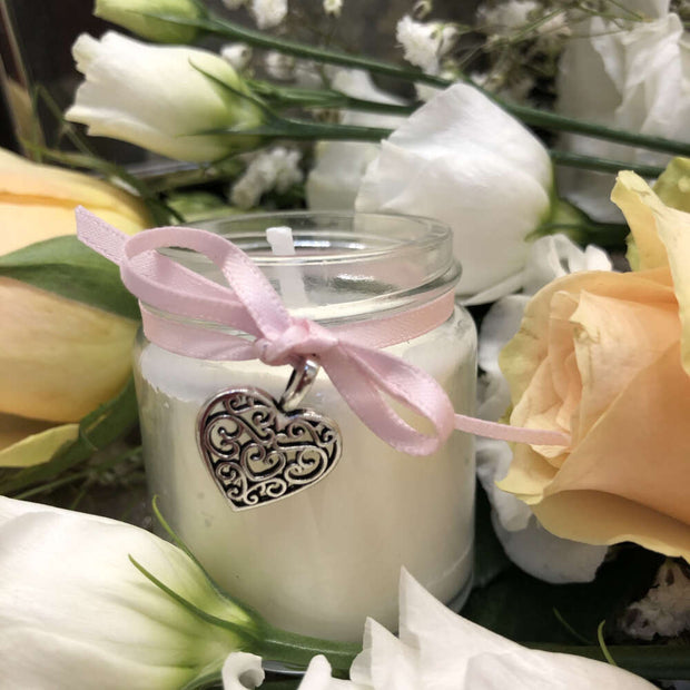 handmade soy wax candle with pink ribbon surrounded by roses