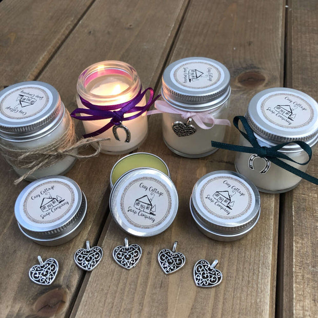 soy wax candles and natual lip balms lined up on a wooden work top with love hearts